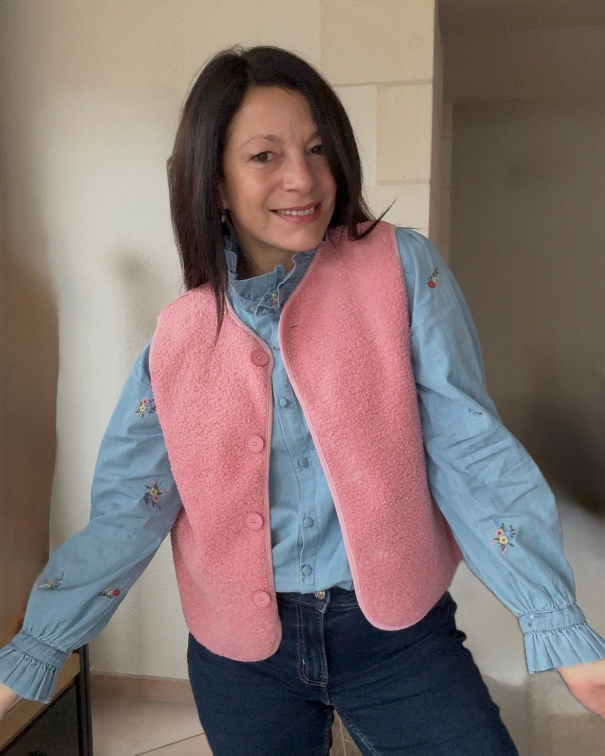 carole 's qui porte le gilet sans manche rose sur la chemise en jean 
